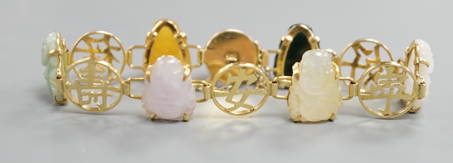 A Chinese 14k yellow metal and hardstone set bracelet, with alternating character and six carved Buddha set links, approx. 17cm, gross weight 17.3 grams.